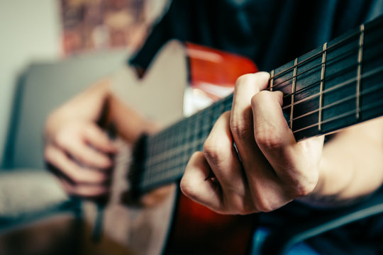 young musician playing acoustic guitar, live music background