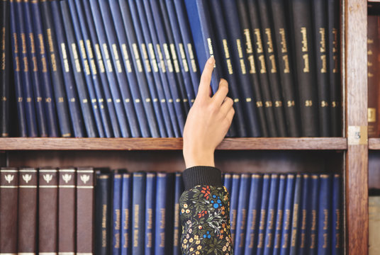 Human hand choosing book from shelf