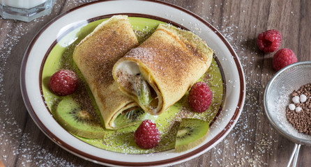 Homemade pancake with curd, raspberries, kiwi and banana pieces sprinkled with cocoa