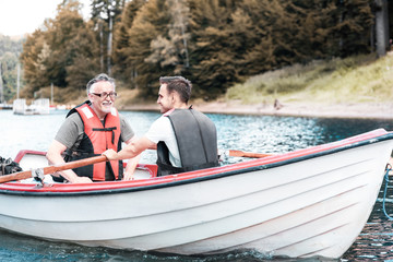 Two men rowing a boat on the tranquil lake .