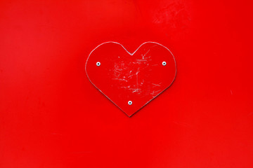 Scratched red metal heart on red background