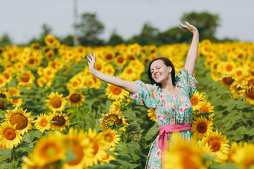 Naklejka na ściany i meble Brunette girl in a field of sunflowers