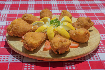 fried chicken legs arranged on wooden plate with parsley lemon tomato