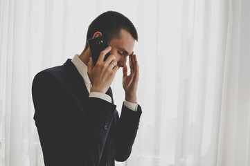 Toned image of concentrated man speaking over phone while working. Business or freelance concept.