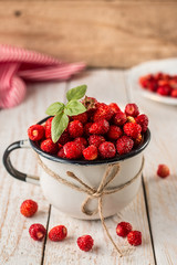wild strawberry in a white Cup on wooden background