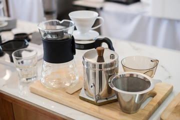 Drip coffee or pour over coffee brewing equipment set consisting of filter, kettle, scale, and cup.