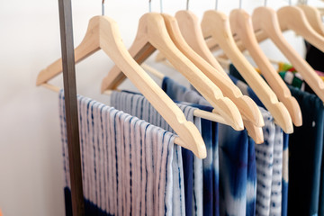 Tie dye shirts and clothing hanging on rack collection in fashion store. Concept of traditional handmade tie-dye clothes.