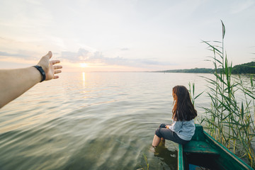 first person view , man looking on girl that sitting on old boat and looking on sunrise