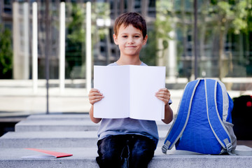 Little boy holding blank open notebook with copy space for text