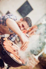 Obraz na płótnie Canvas Young man preparing barbecue outdoors
