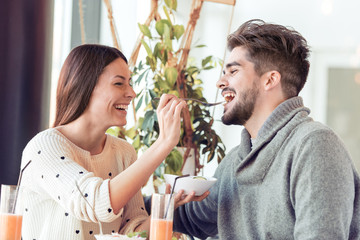 Happy couple eating salad for lunch at cafe
