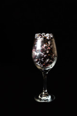 Ice glass with black frozen currant and ice on a black background