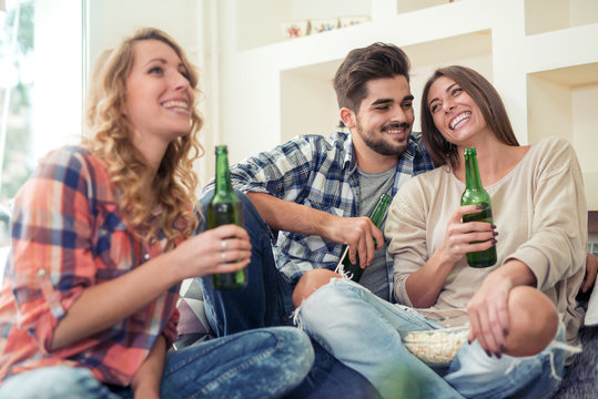 Friends having a good time, drinking beer together at home.