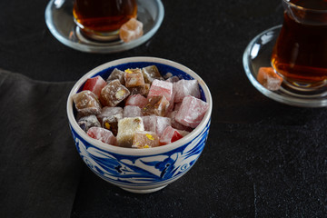 Delicious Turkish delight with tea on a black background. Turkish lukum.
