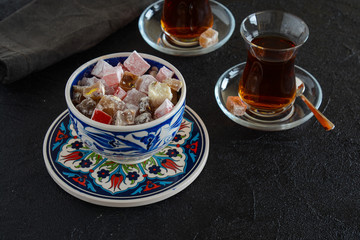 Delicious Turkish delight with tea on a black background. Turkish lukum.