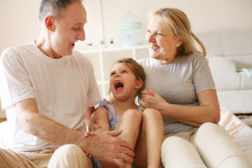 Grandmother and grandfather sitting together with their granddaughter.