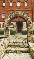 Brick arch with stairs in front of the building with windows