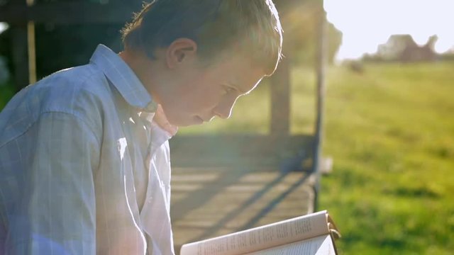 A blond haired boy reads a book