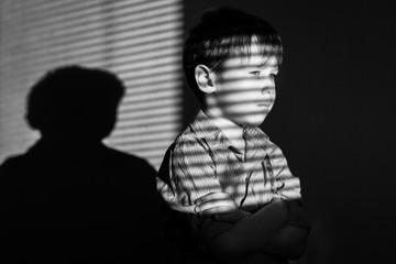 Black and white photo of a boy in a shirt in the shade of the blinds - 167078458