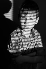 Black and white photo of a boy in a shirt in the shade of the blinds - 167078487