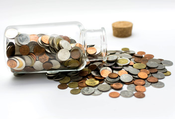 Thai bath coins spilling out of a glass jar.