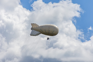 White airship of a soft system with stabilizers and a motor hovers in the sky © IKvyatkovskaya