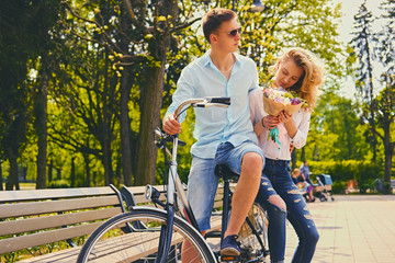 A couple riding on the bicycle in a park.