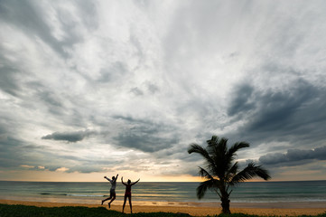 Guy and girl having fun at sunset by the sea. Friends by the sea. Guys have fun at sunset. Cheerful silhouettes at sunset