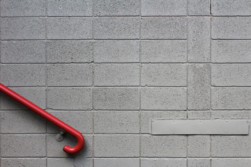 Red hand rail against a grey cinder block wall
