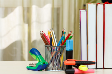School supplies. Books, colour pencils, markers, stapler on wooden table