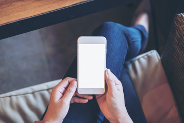 Mockup image of woman's hands holding white mobile phone with blank screen on thigh in office