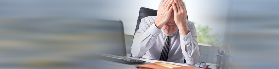 Stressed businessman with head in hands