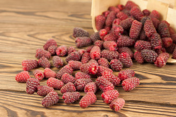 Red fresh raspberries in bascet on old wooden background.
