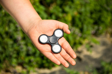 Boy playing with fidget spinner stress relieving toy outdoor