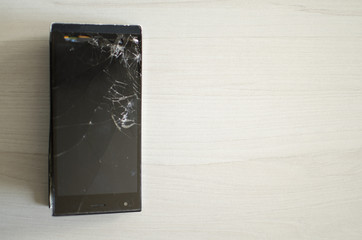 Broken phone. Cracked sensor. Bloated phone battery on the wooden background