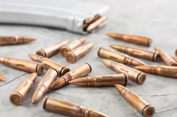 Silver full magazine for assault rifle and scattered bullets on old grey broken concrete