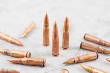 Three metal bullets and many scattered bullets for assault rifle on old grey broken concrete