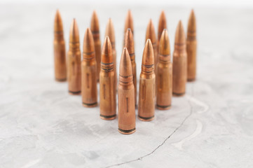 Triangle of metal bullets for assault rifle on old grey broken concrete