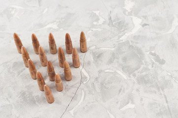 Triangle of metal bullets for assault rifle on old grey broken concrete