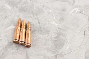 Three metal bullet for assault rifle on old grey broken concrete