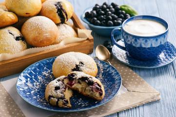 Homemade blueberry filled buns on wooden table.
