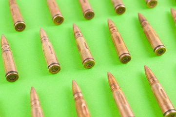 Row of many metal bullets for assault rifle on green background