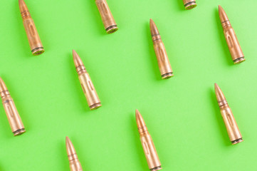 Fototapeta na wymiar Row of many metal bullets for assault rifle on green background