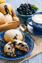 Homemade blueberry filled buns on wooden table.