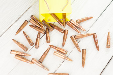 Scattered from a yellow paper packet of a bullets on old rustic white wooden planks