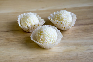 Fototapeta na wymiar Raw coconut balls in paper cupcakes