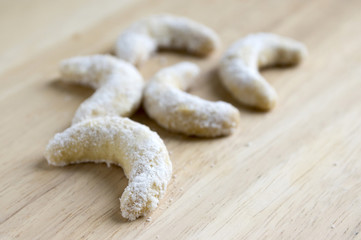 Tiny vanilla crescents, vanilla rolls on wooden table, coated in icing sugar, white