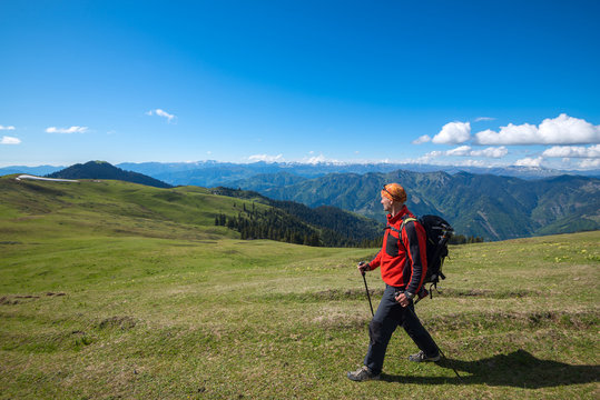 Man adventurer goes along alpine meadow