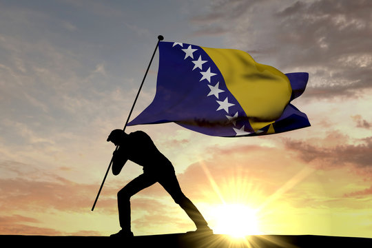 Bosnia flag being pushed into the ground by a male silhouette. 3D Rendering