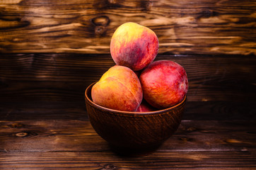 Peaches in a bowl on wooden table